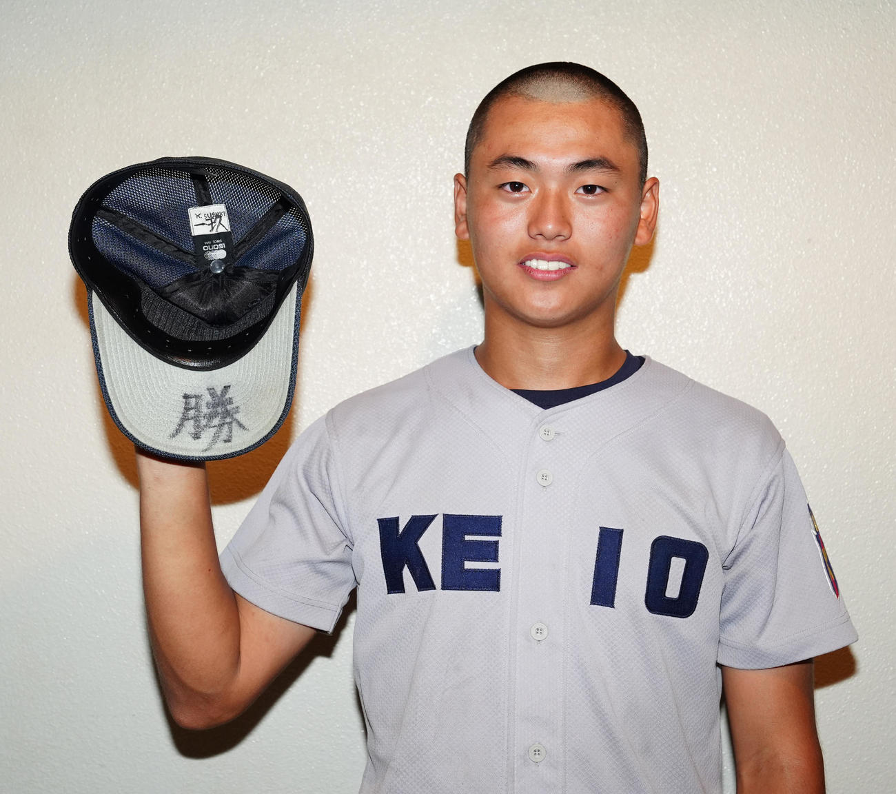 慶応対横須賀学院　試合後、帽子のつばに記した「勝」の文字を披露する慶応・酒井（撮影・江口和貴）