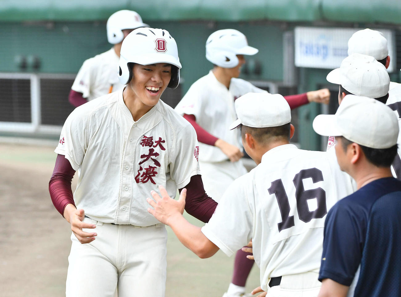 福岡大大濠対福岡大若葉　1回表福岡大大濠2死二、三塁、豊田の2点適時左二塁打で生還し、ナインと笑顔でタッチを交わす柴田（撮影・岩下翔太）
