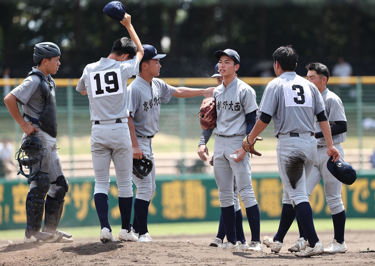 【京都】京都国際対京都外大西　4回裏、ピンチを迎えた京都外大西の先発田中（右から3人目）はナインの激励を受ける（撮影・西尾就之）