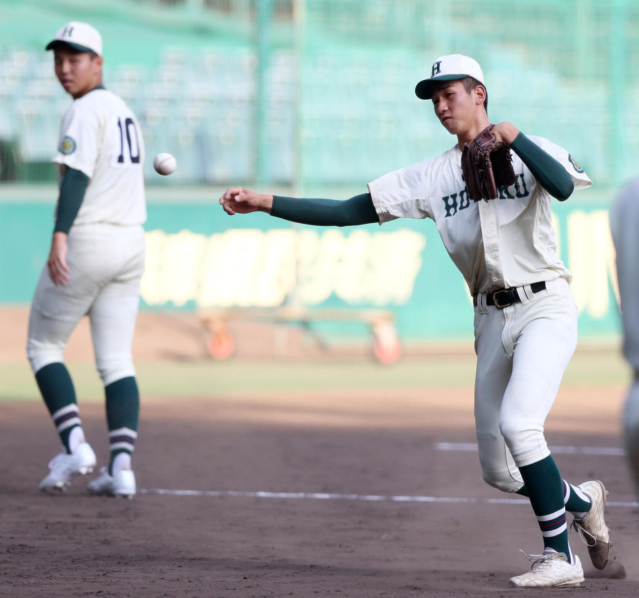 2024年8月2日、甲子園で練習でノックを受ける報徳学園・今朝丸裕喜。左奥は間木歩