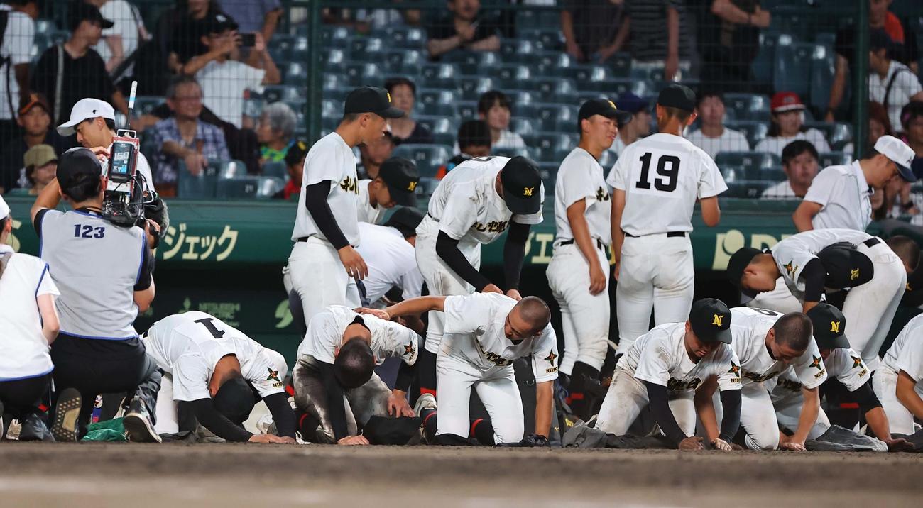 札幌日大対京都国際　涙を流しながら甲子園球場の土を集める札幌日大エース小熊（左）らナイン（撮影・上田博志）