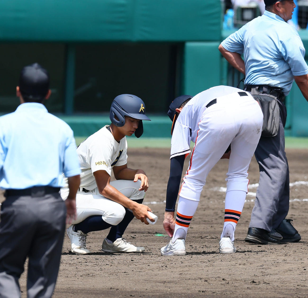 木更津総合対神村学園　5回裏神村学園1死、今村の打球を足に受け相手の照屋（左）からコールドスプレーで処置を受ける木更津総合・千葉（撮影・加藤哉）
