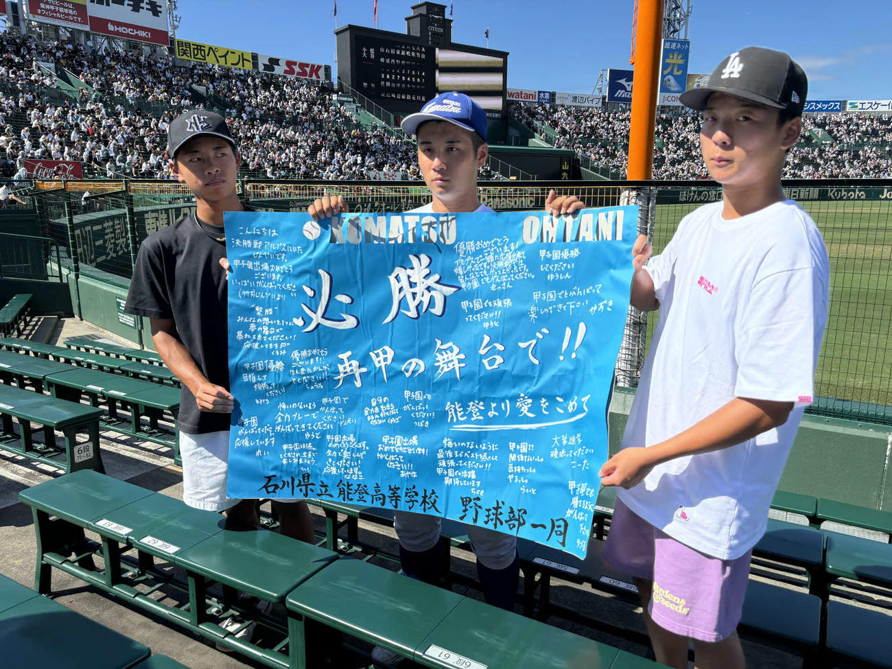 能登野球部から贈られた応援メッセージボードを持つ（右から）能登の竹下仁平くん（3年）、小松大谷学生コーチの梅田栄太朗くん（3年）、能登の新出〓（草カンムリに来の旧字体）杜投手（1年）（撮影・古財稜明）