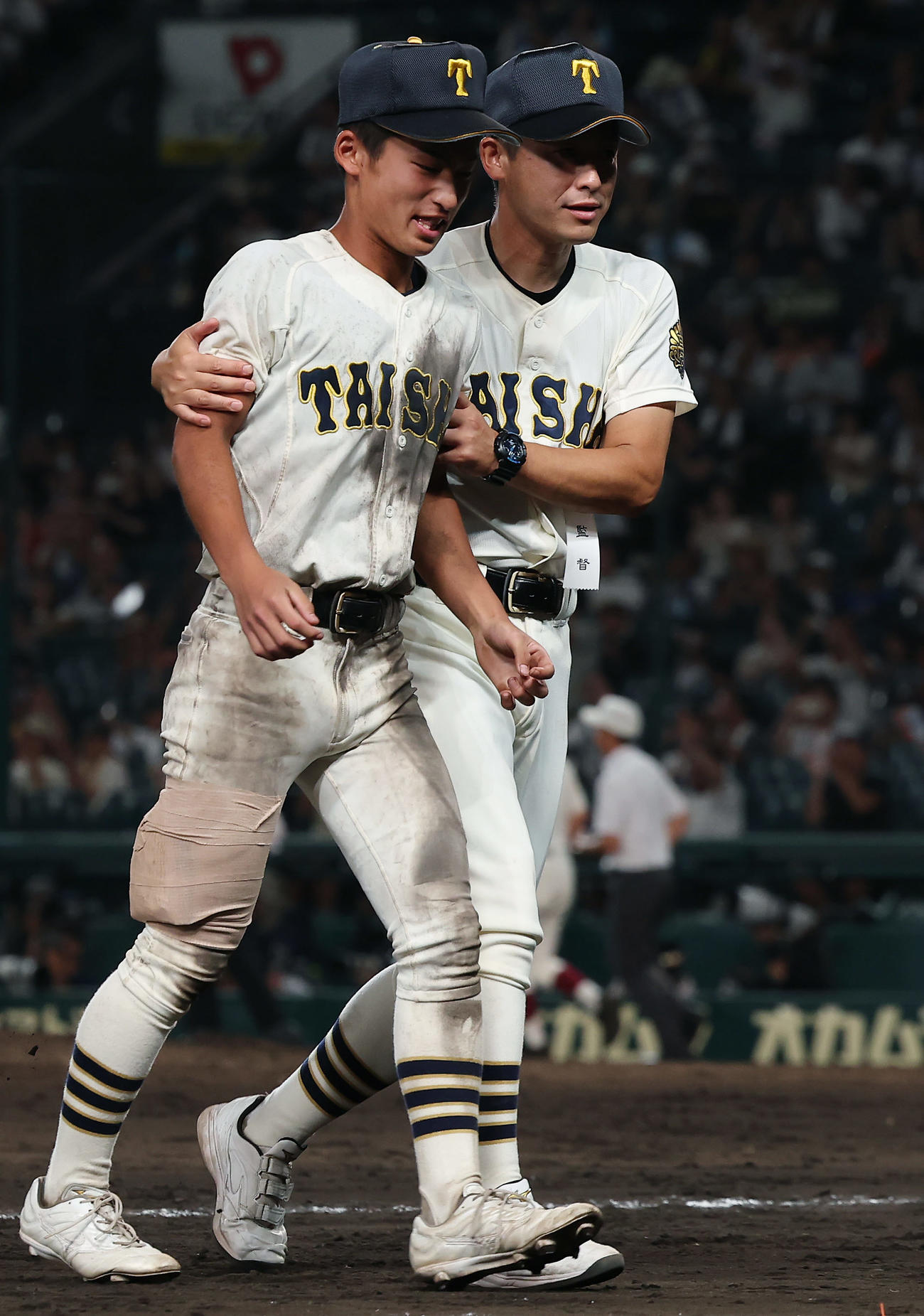 早実対大社　ケガで途中交代した大社・高橋（左）は、おぶってもらい応援団のもとに向かおうとするも石飛監督に制止される（撮影・前田充）