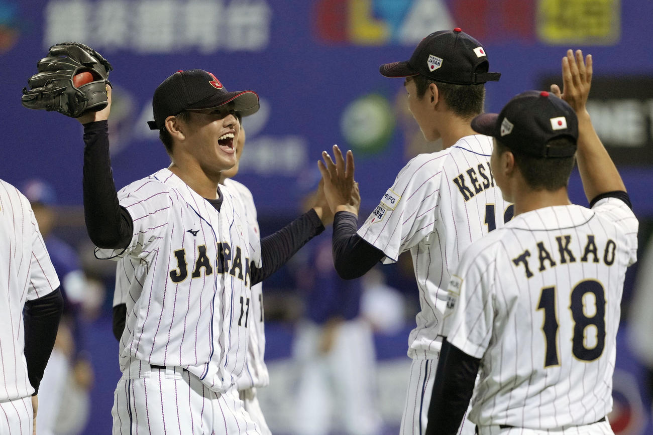 台湾に勝利し、笑顔でタッチを交わす坂井（左）ら高校日本代表（共同）