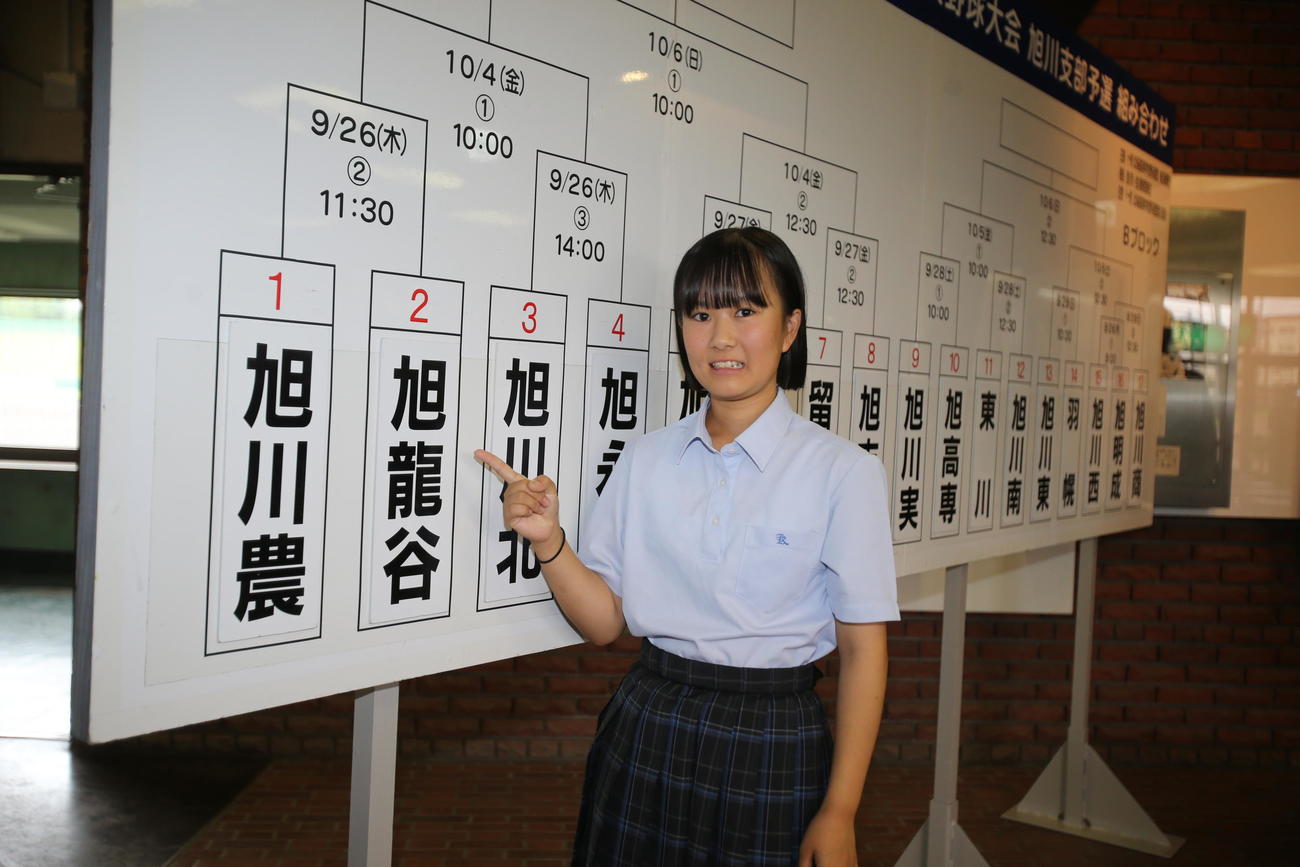 旭川龍谷の小玉主将は、組み合わせ抽選会のボードの前で笑顔（撮影・中島洋尚）