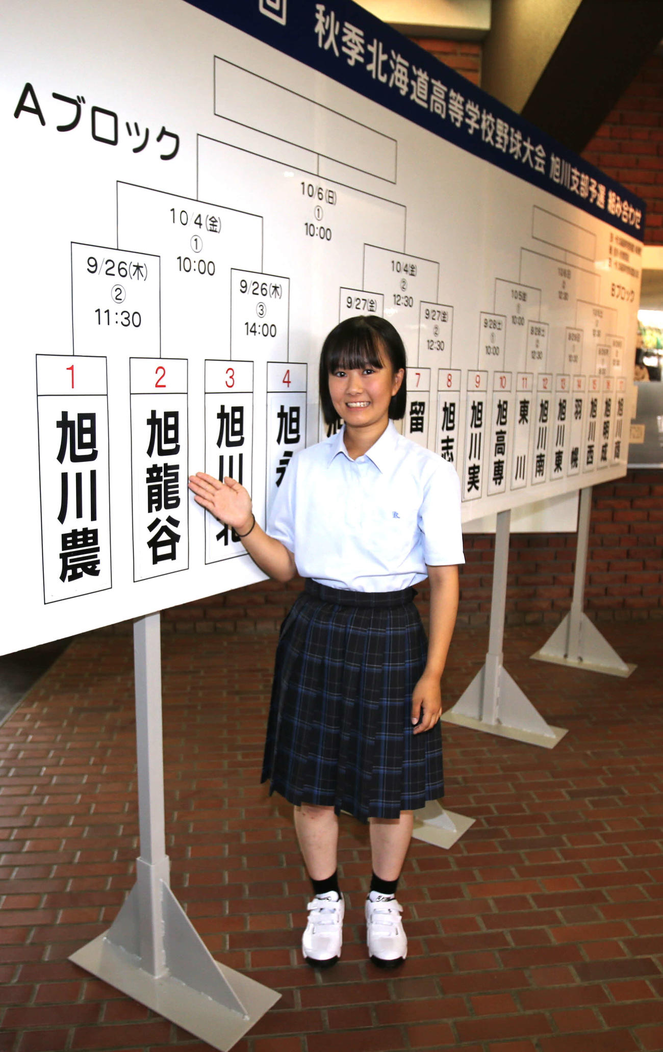 旭川龍谷の小玉主将は、組み合わせ抽選会のボードの前で笑顔（撮影・中島洋尚）
