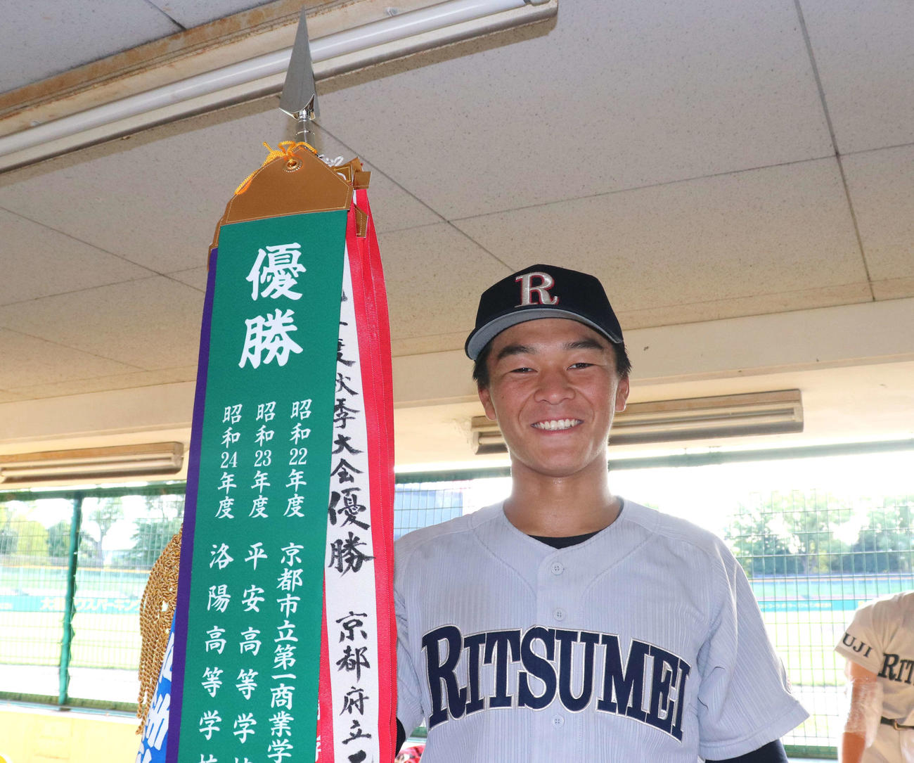 龍谷大平安との京都大会決勝　優勝旗を手に笑みを浮かべる、決勝打を放った立命館宇治の主将・伊藤