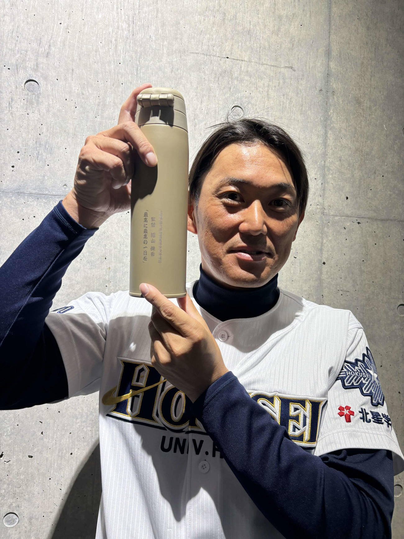 ナインからの誕生日プレゼントの水筒を手に笑顔を見せる北星学園大付の沼山監督（撮影・保坂果那）