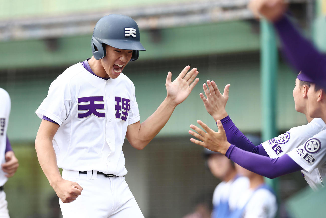 滋賀短大付対天理　7回裏天理1死二、三塁、永末の2点適時二塁打で生還し、ナインとなっちを交わす赤埴（撮影・前田充）