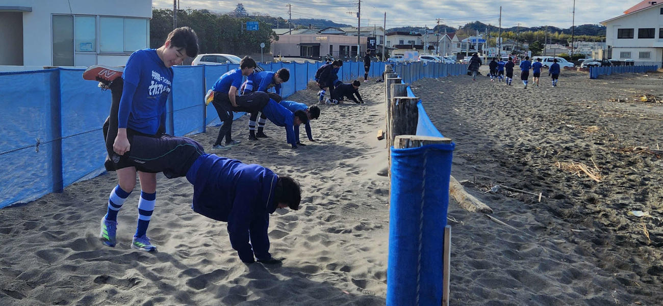 中央学院・館山キャンプ、砂浜で手押し車で横に進むトレーニングで汗を流す中央学院の投手たち（撮影・保坂淑子）