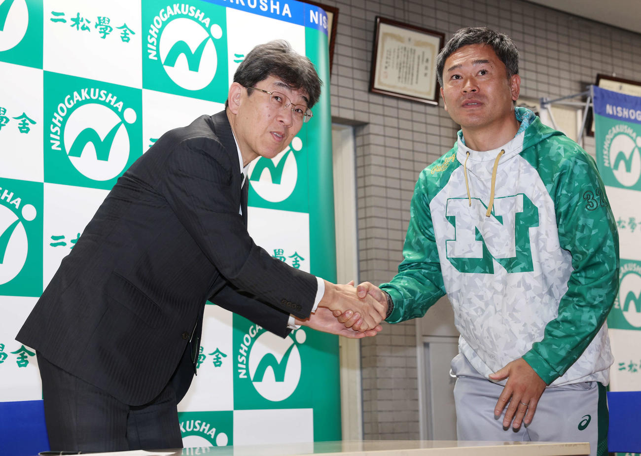 センバツ出場を決め握手する二松学舎大付・鵜飼校長（左）と立野部長（撮影・宮地輝）