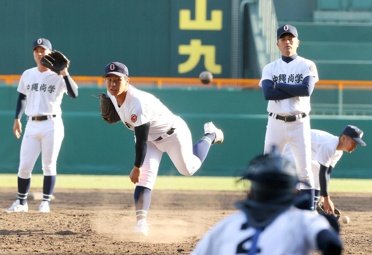 甲子園のマウンドで投球練習をする沖縄尚学エース末吉（左から2人目）の投球を見る比嘉監督（右から2人目）（撮影・上山淳一）