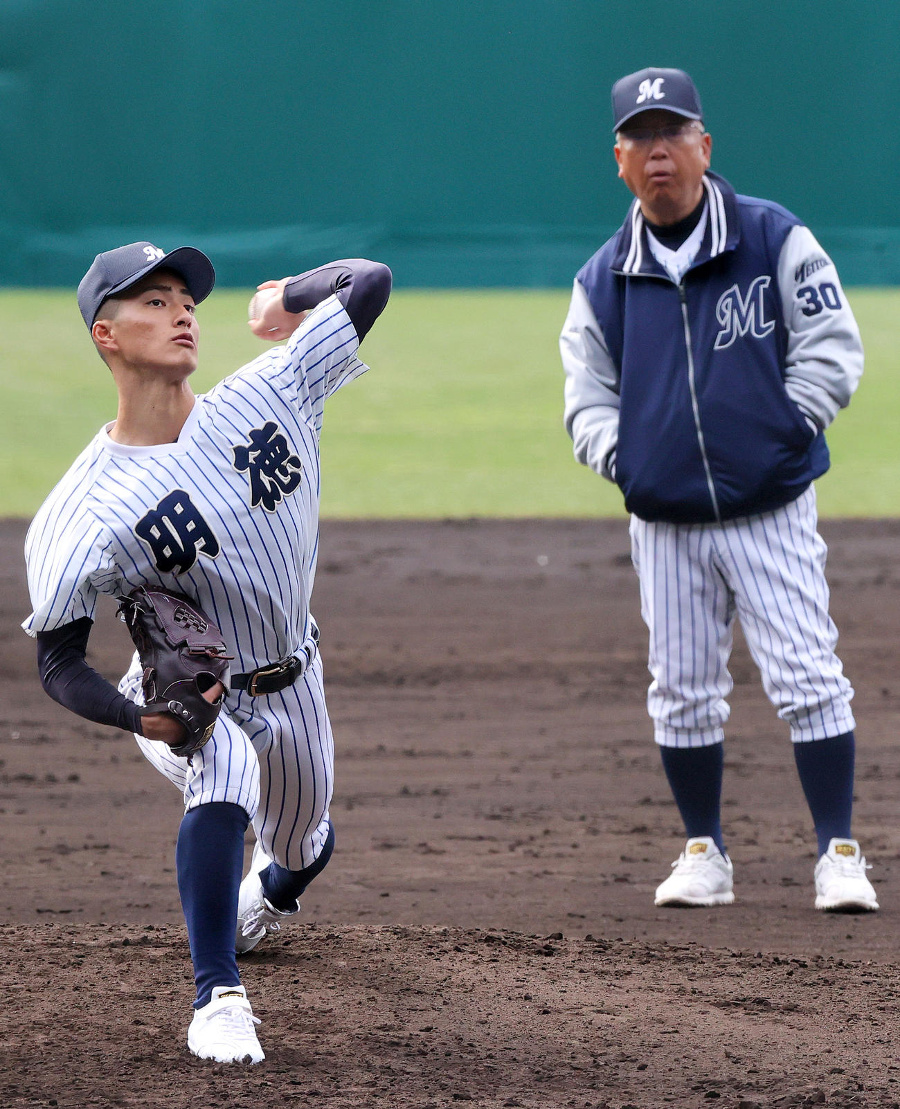 甲子園のマウンドで投球する明徳義塾エース池崎（左）の投球を確認にする馬淵監督（撮影・上山淳一）
