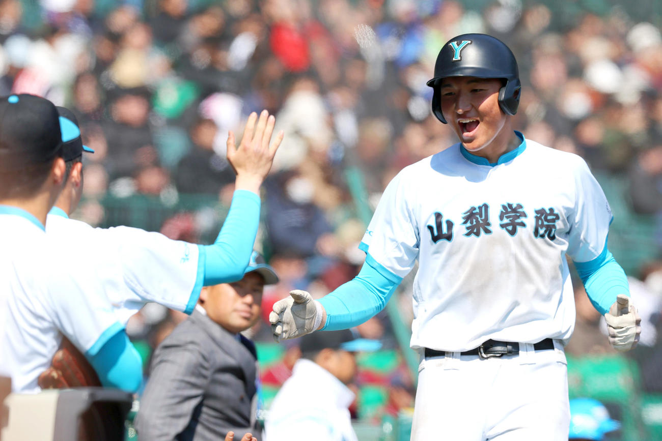 山梨学院対天理　9回表山梨学院2死一、三塁、三走・菰田（右）は平野の中前適時打で生還しベンチ前で喜ぶ（撮影・上山淳一）