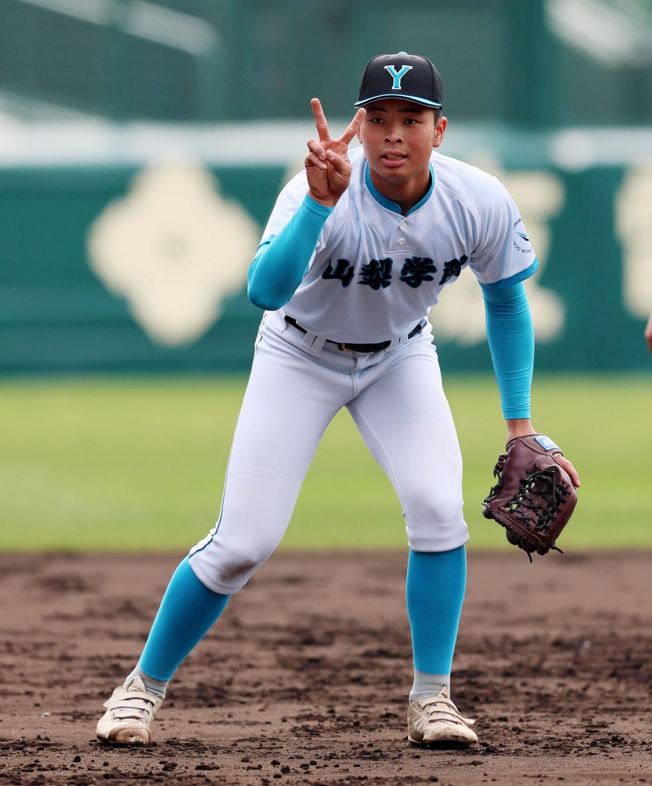 25年3月13日　三塁でノックを受ける前にVサインを見せる山梨学院・梅村主将