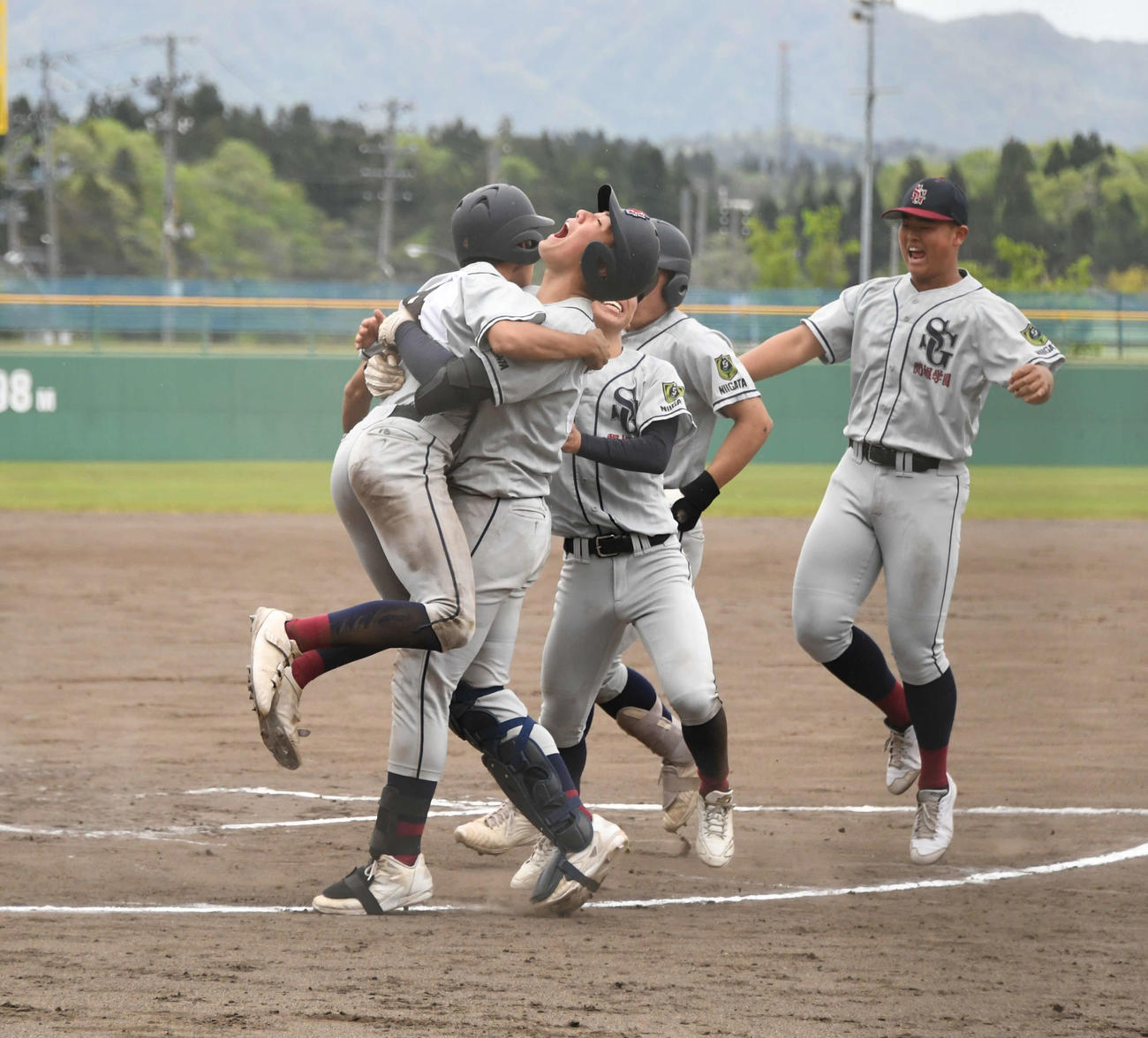関根学園は2－2の10回裏無死満塁、2番高木が中前にサヨナラ打。ホームを踏んだ三塁走者の植木（左）にナインが駆け寄る
