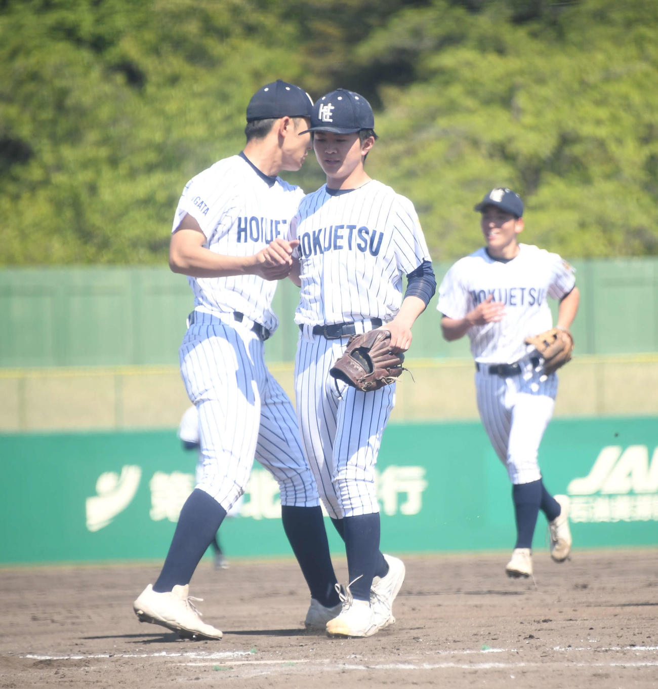 北越対柏崎　マウンドを下りてチームメートとタッチする北越の手戸（中央）