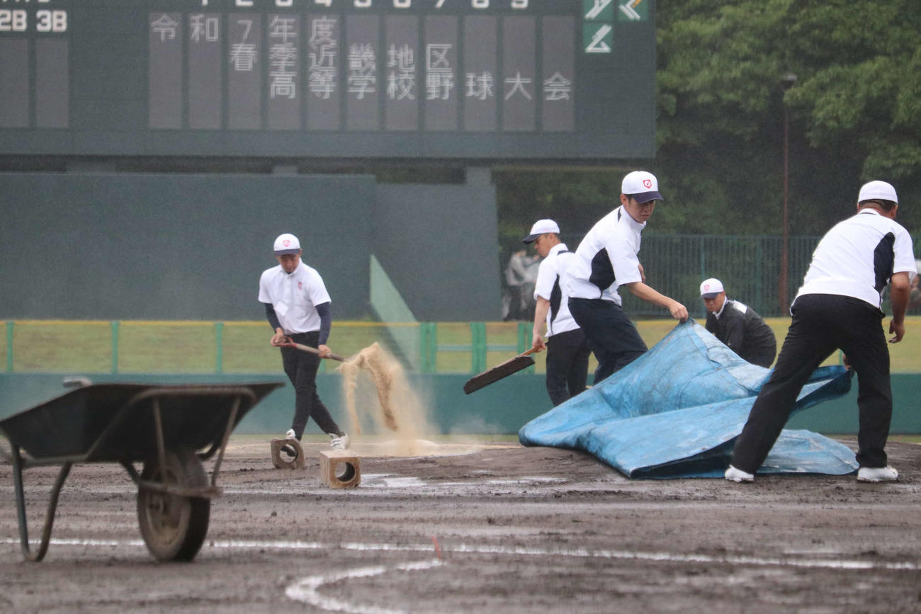 近畿大会1回戦　大阪桐蔭対東洋大姫路　試合前に、雨脚が強くなるも試合開始に向けてシートをはがし、グラウンドに土を足す高野連のスタッフたち（撮影・中島麗）