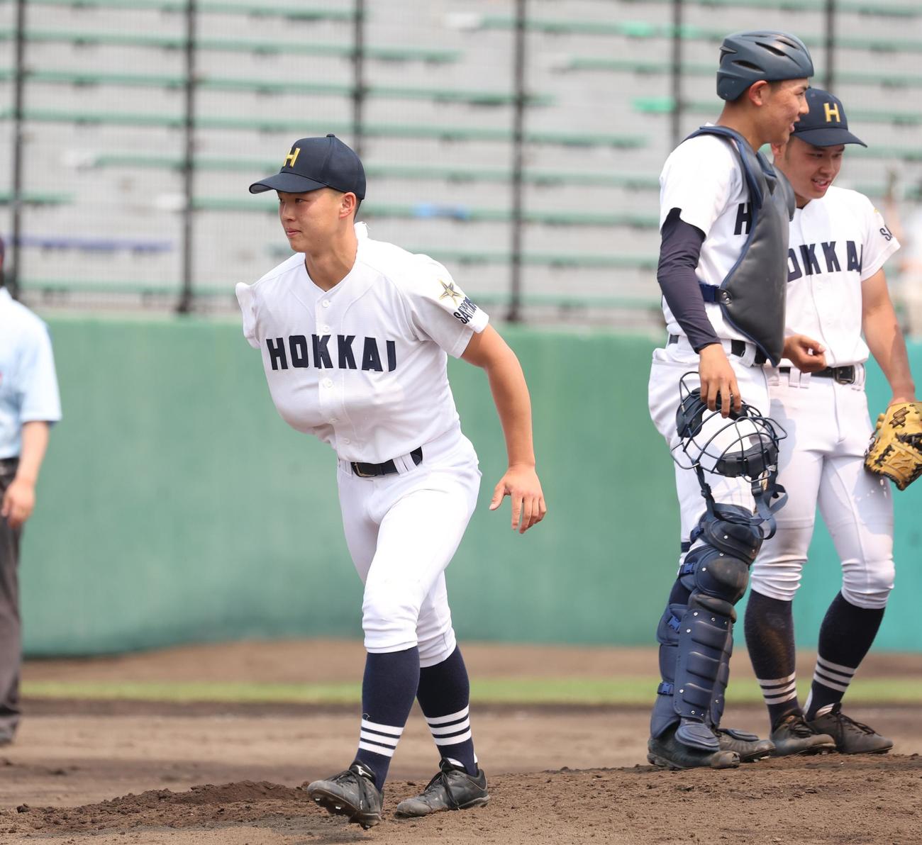 東海大札幌対北海　6回表、2回に守備で負傷した北海・佐藤は右腕を固定し伝令に行く（撮影・黒川智章）