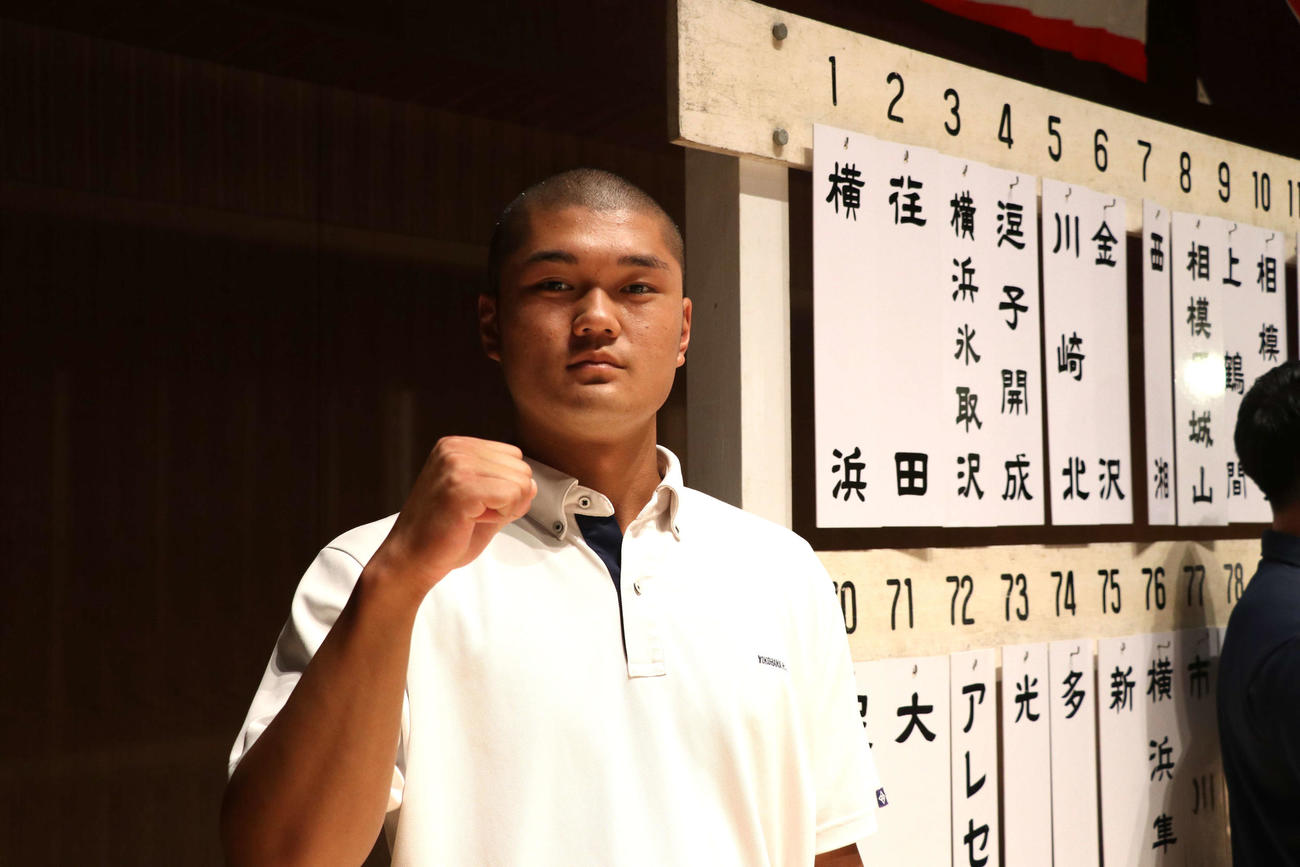 抽選会を終え、校名の札の前でガッツポーズをする横浜主将の阿部葉（撮影・寺本吏輝）