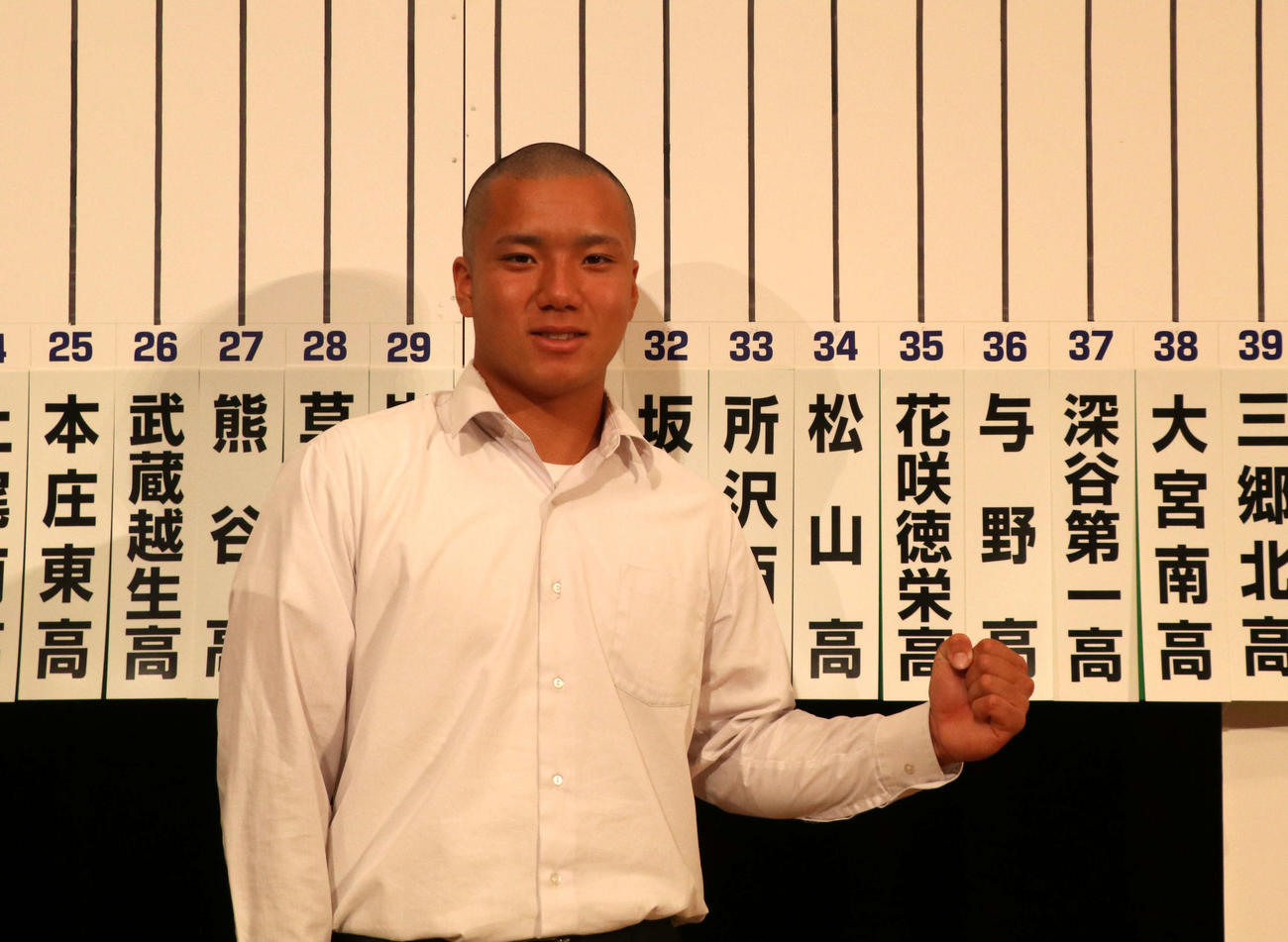 校名の札の前でガッツポーズをする花咲徳栄・酒井主将（撮影・山本佳央）