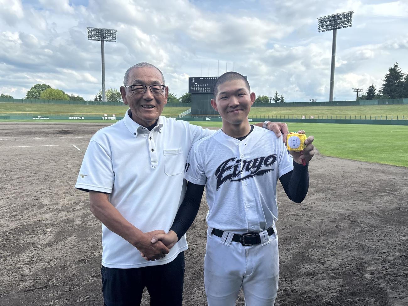 甲子園の土入りお守りを持つ旭川永嶺の角家（右）と祖父の元旭川実監督・込山氏（撮影・保坂果那）