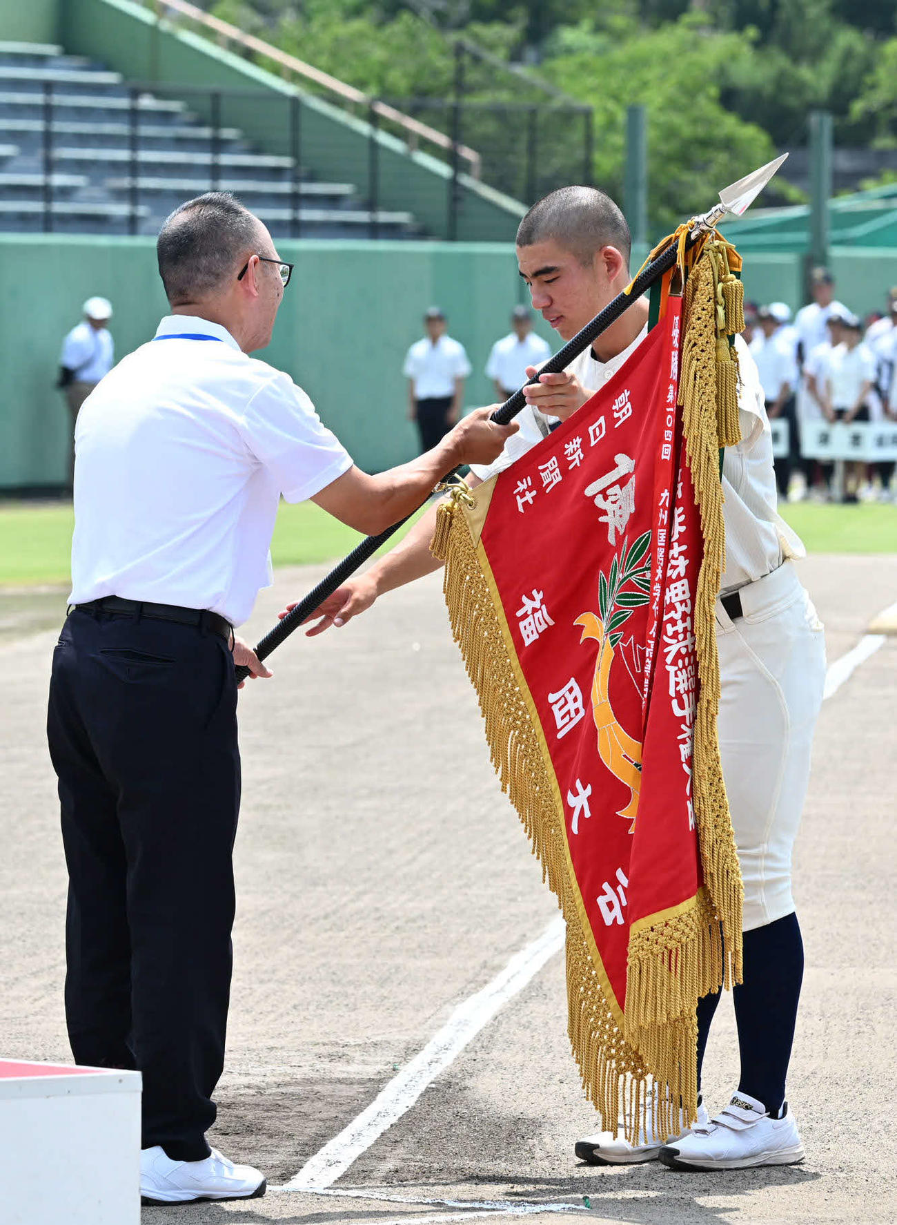 高校野球福岡大会の開会式で優勝旗返還を行う西日本短大付・小川主将（右）（撮影・林敢治）