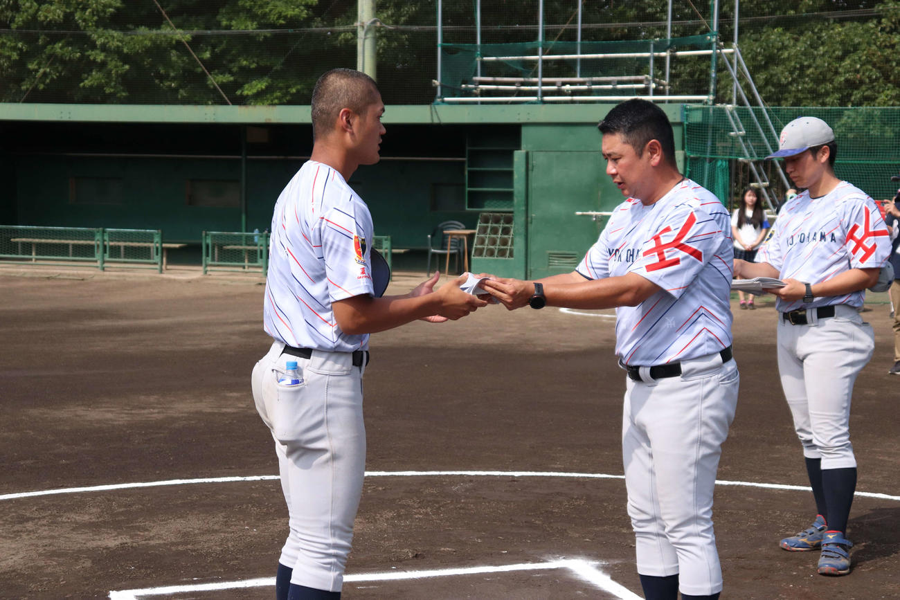 夏の県大会、ベンチ入り20名の背番号渡しで、村田浩明監督から背番号8を受け取る、主将の阿部葉（撮影・保坂淑子）