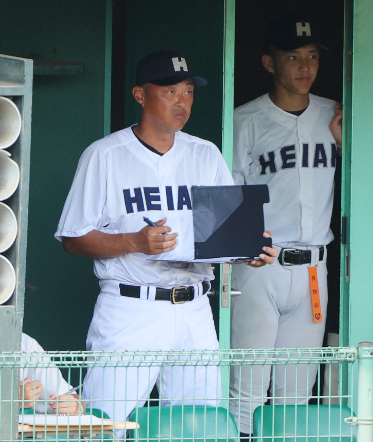 京産大付対龍谷大平安　龍谷大平安の川口監督（手前）はメモを取りながら試合を見つめる（撮影・上山淳一）
