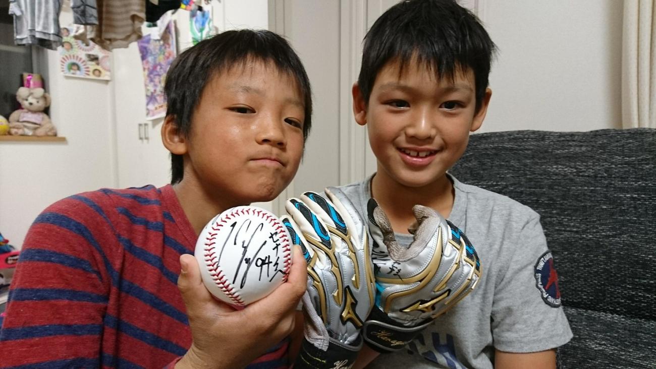 阪神原口のサイン入りボールと打撃用手袋を持つ小学生時代の阪下颯那（左）と阪下漣（阪下卓さん提供）