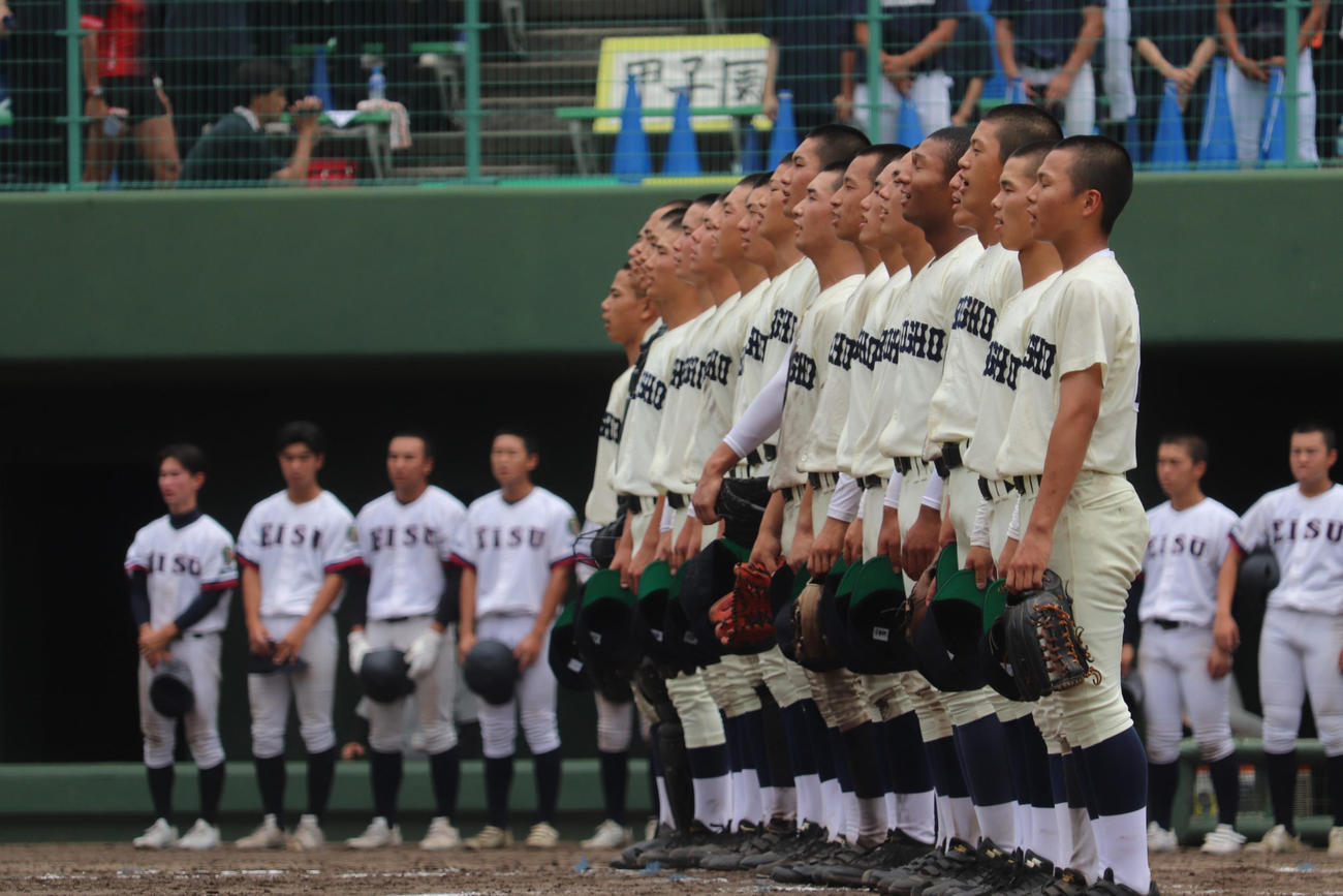 広島大会3回戦　英数学館対広島商　勝利の校歌を斉唱する広島商ナインを苦い表情で見つめる、英数学館ナイン（撮影・中島麗）