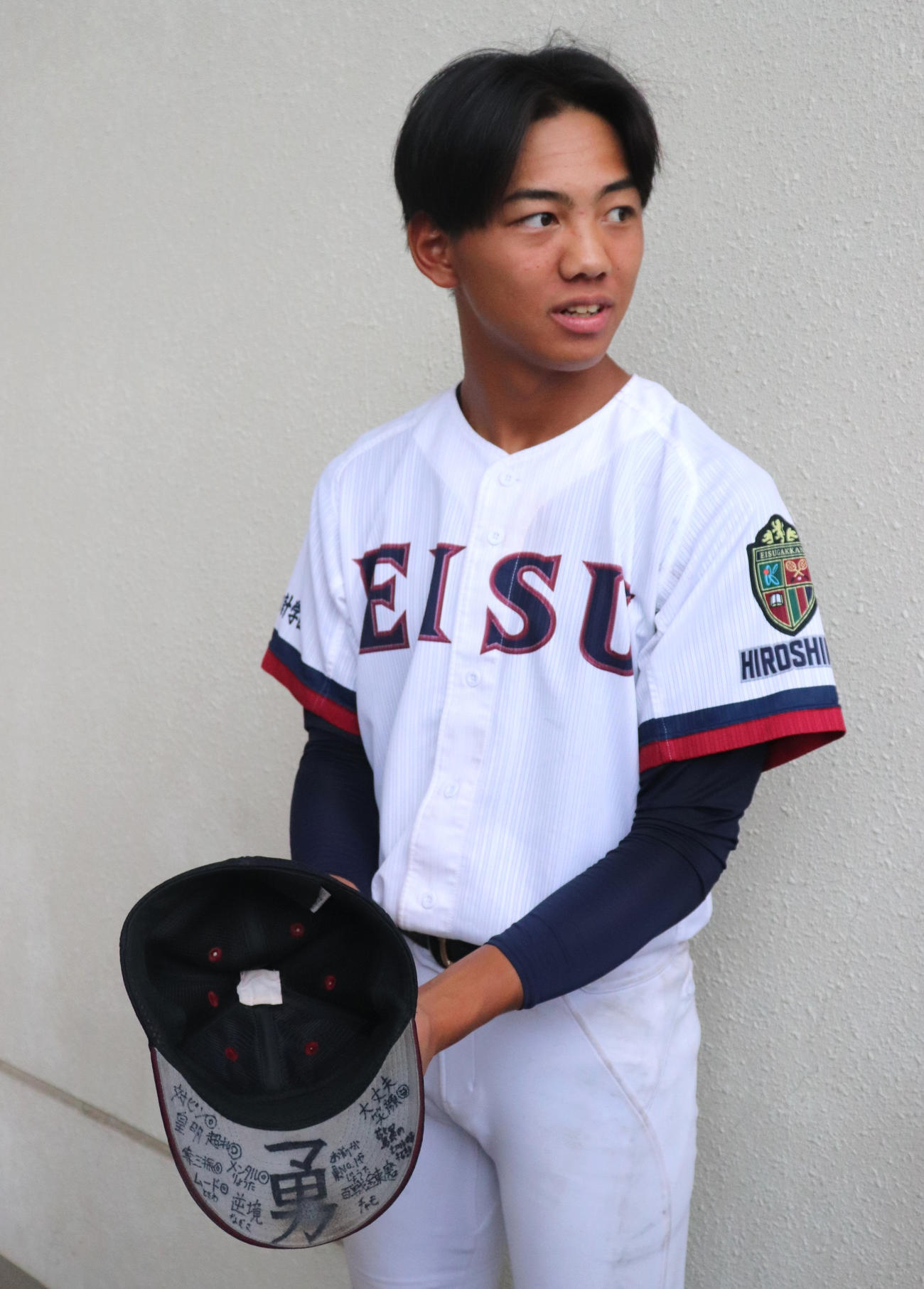 広島大会3回戦　英数学館対広島商　試合後、報道陣にチームメートが書いた帽子のつばのメッセージを見せる英数学館の藤本（撮影・中島麗）