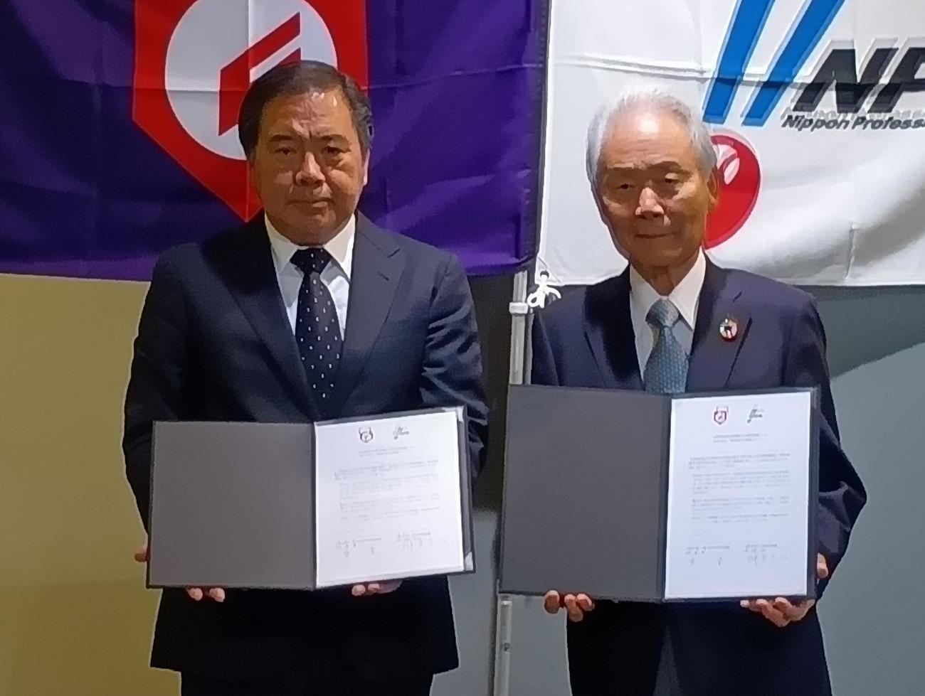 日本高野連とNPBによる野球振興事業の連携合意書を掲げる高野連の宝馨会長（左）とNPB榊原定征コミッショナー