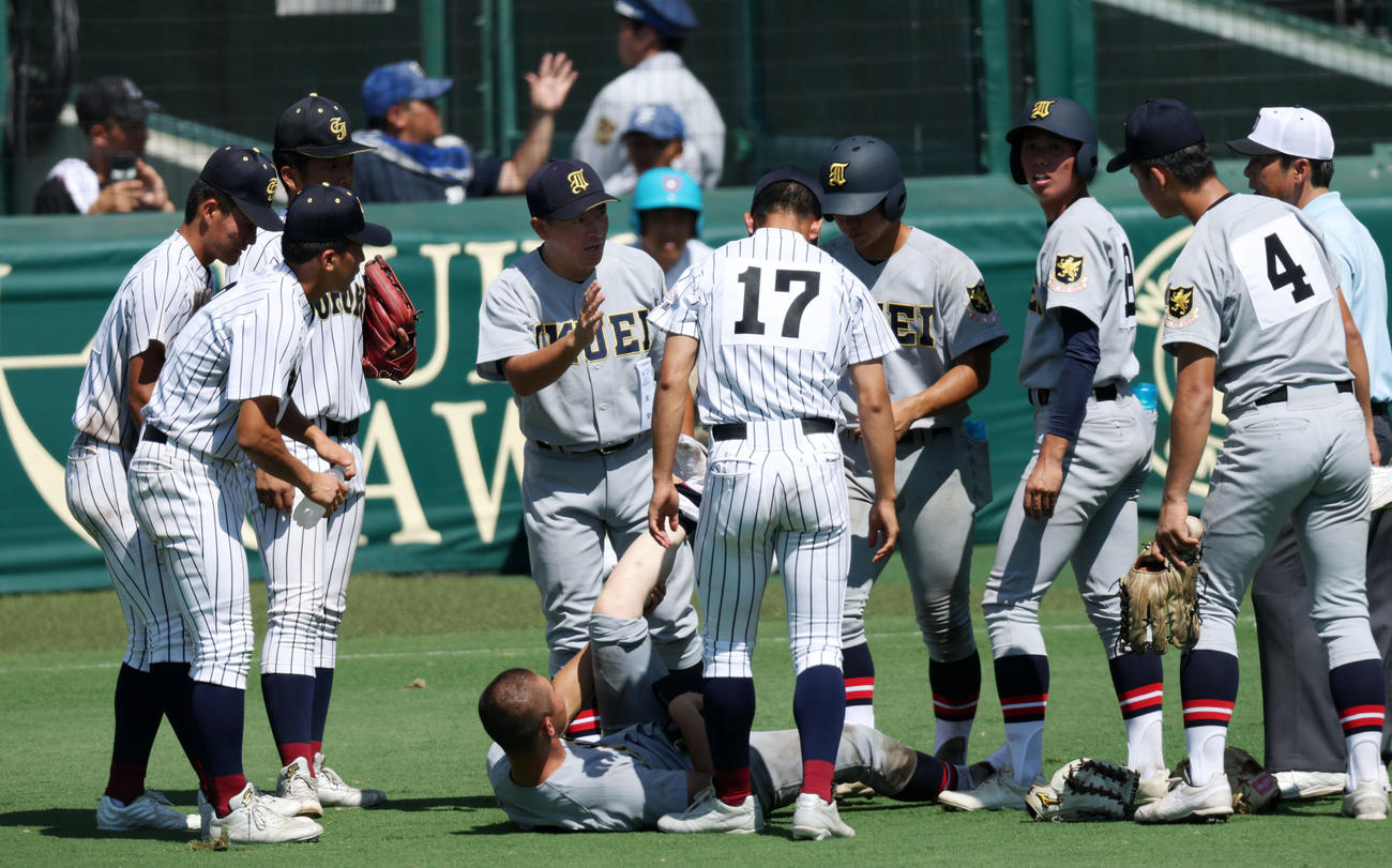 仙台育英対鳥取城北　8回裏を終えベンチへ引き揚げられずその場に座り込んだ仙台育英・田山纏（中央）に対し、水分補給やマッサージなどの手助けを行った鳥取城北ナインに謝意を伝える須江監督（撮影・加藤哉）