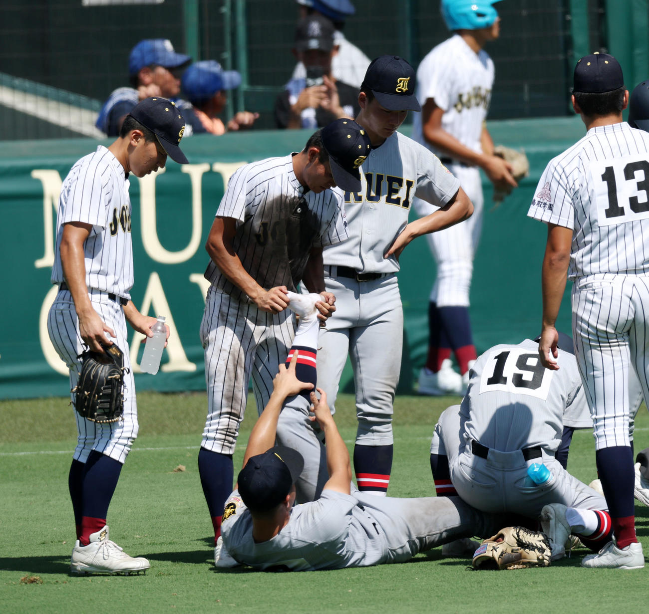 仙台育英対鳥取城北　8回裏を終えベンチへ引き揚げられずその場に座り込んだ仙台育英・田山（中央）に対し、水分補給やマッサージなどの手助けを行った鳥取城北ナイン（撮影・加藤哉）