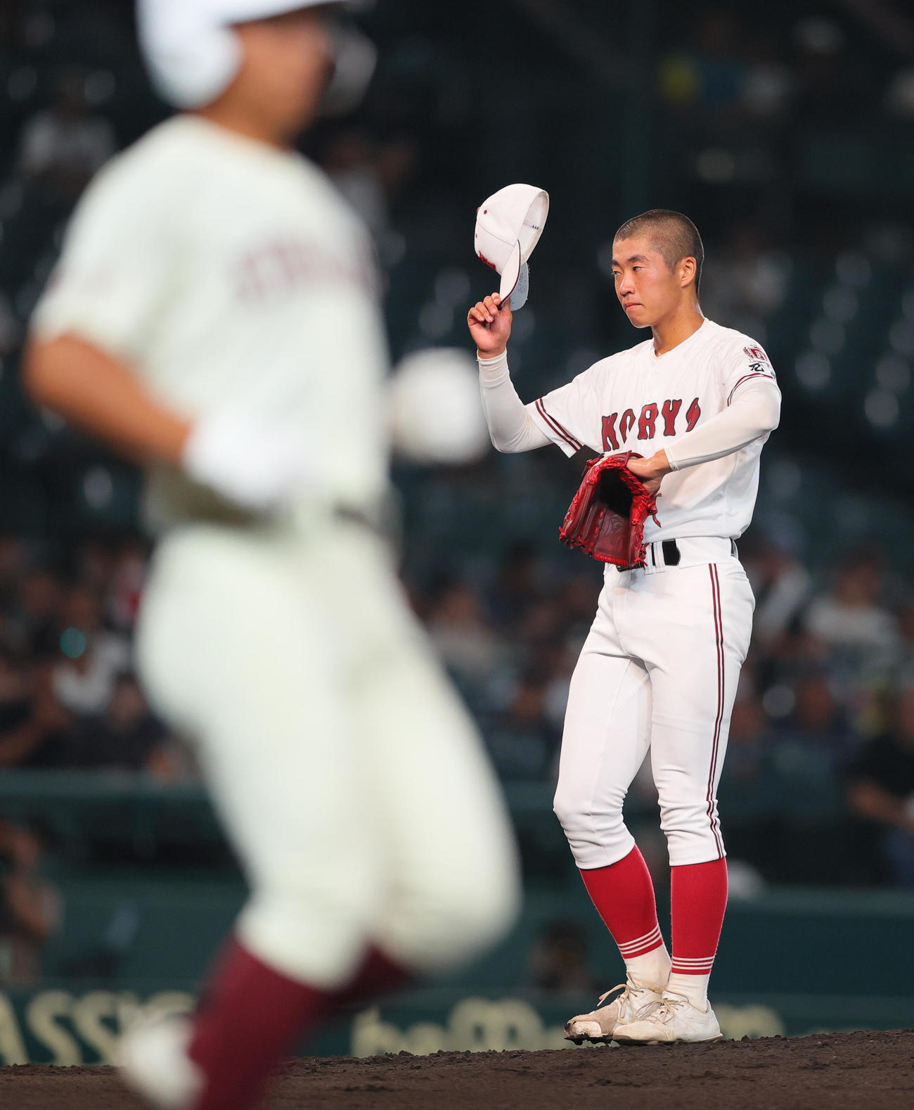 旭川志峯対広陵　2回表旭川志峯2死三塁、堀田は村田に死球を与え、帽子を取って謝る（撮影・上山淳一）