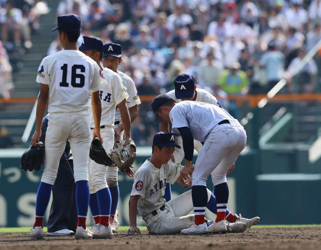 横浜対綾羽　8回途中、足の治療中に横浜の選手から水を手渡される綾羽・経免（中央）（撮影・藤尾明華）