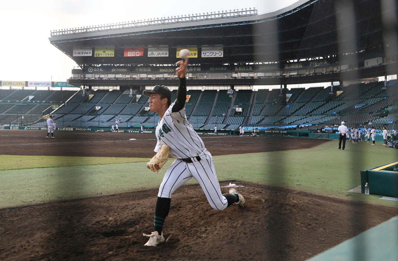 シート打撃を行うナインをバックにブルペンで投球練習する津田学園・桑山晄太朗（撮影・宮崎幸一）