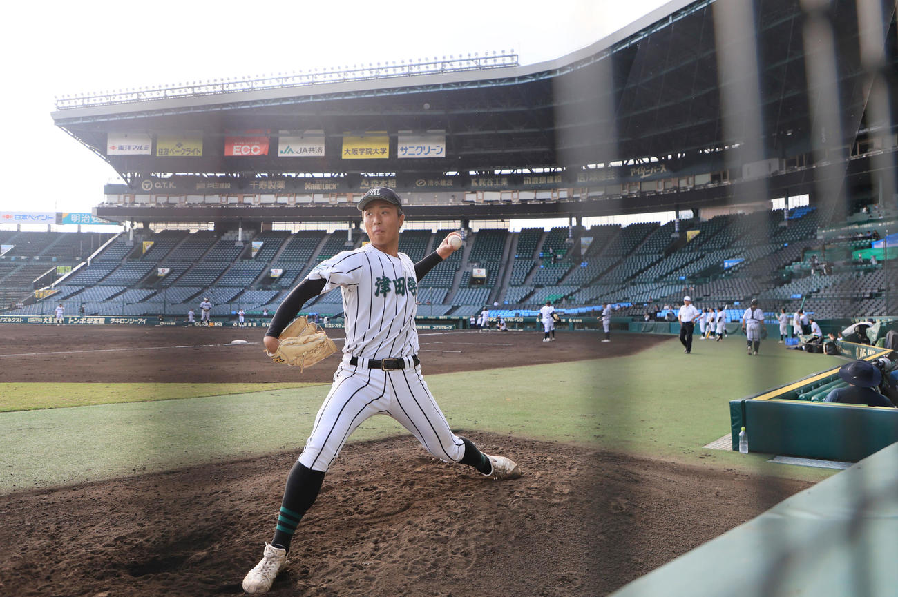 シート打撃を行うナインをバックにブルペンで投球練習する津田学園・桑山晄太朗（撮影・宮崎幸一）