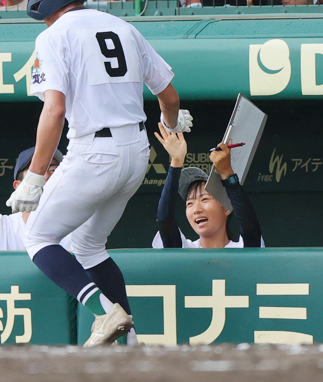 佐賀北対明豊　5回裏佐賀北2死一、三塁、宮崎の右前適時打で生還した山下（手前）を出迎える家永記録員（撮影・上山淳一）