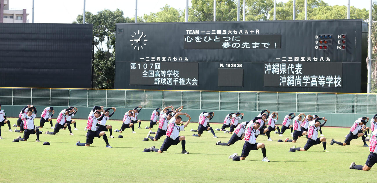 大会キャッチフレーズが表示される中、練習する沖縄尚学ナイン。このキャッチフレーズは沖縄の高校生が作った（撮影・西尾就之）