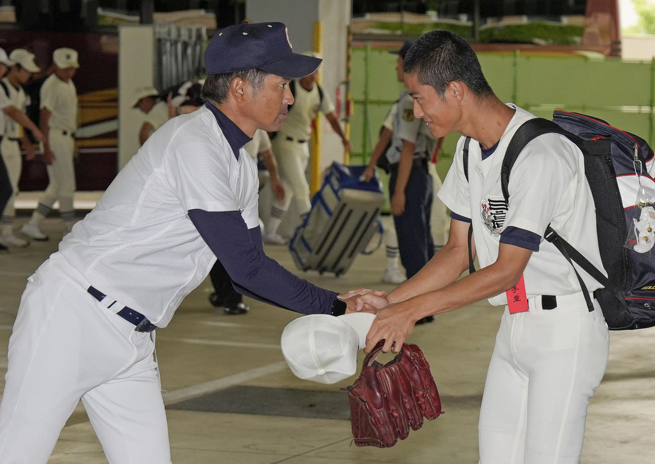 決勝で球場入りする際に、日大三の選手と握手を交わす沖縄尚学・比嘉監督（左）（共同）
