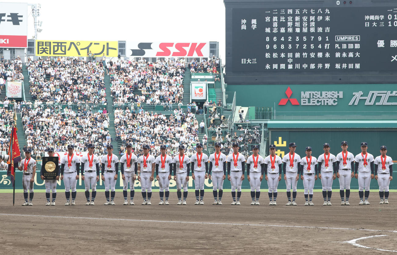 沖縄尚学対日大三　深紅の大優勝旗を持ち整列する沖縄尚学ナイン（撮影・白石智彦）