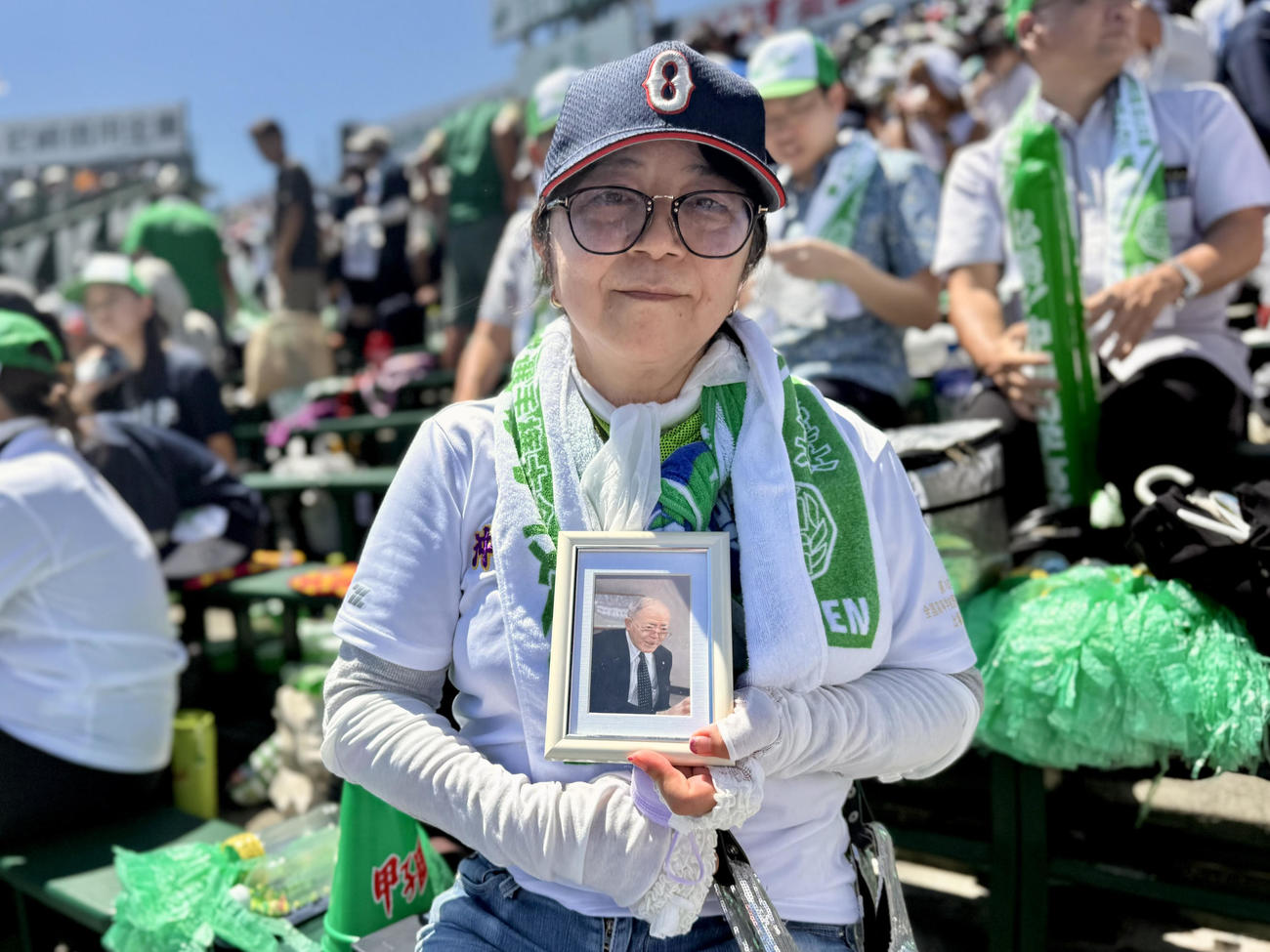 山梨学院対沖縄尚学　前理事長で今夏逝去した名城政次郎氏の遺影を持って応援する沖縄尚学の大城美穂子理事長