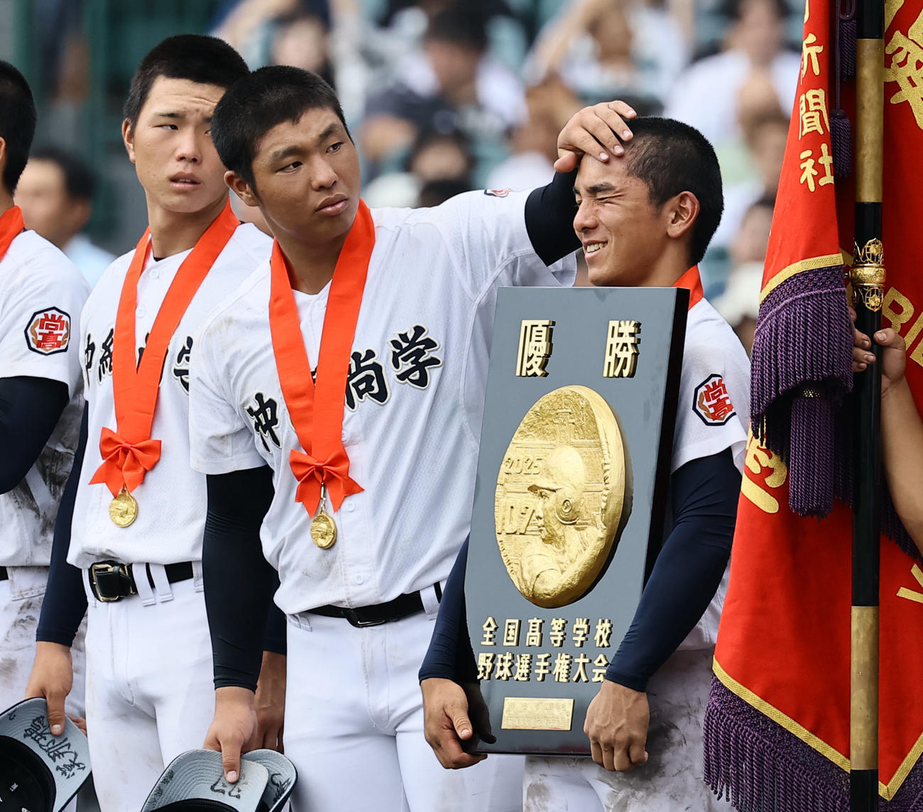 沖縄尚学対日大三　優勝盾を持った嶺井の汗をぬぐう沖縄尚学・末吉（撮影・藤尾明華）