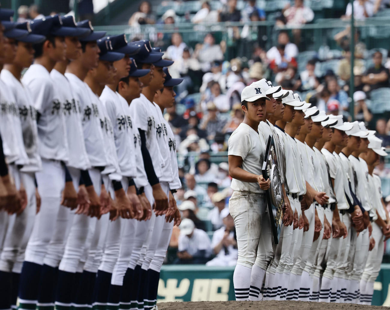 沖縄尚学対日大三　準優勝盾を手に、沖縄尚学ナインに目をやる日大三・本間（中央）（撮影・藤尾明華）