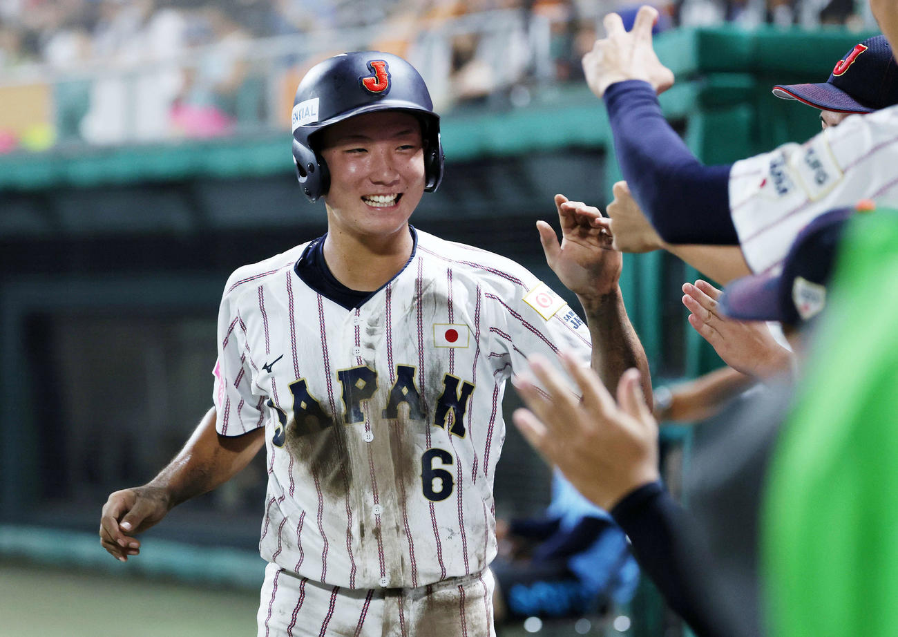 韓国対日本　2回裏日本1死二、三塁、坂本の二ゴロ間に三塁走者の高畑が生還しベンチ前で笑顔を見せる（撮影・鈴木正人）