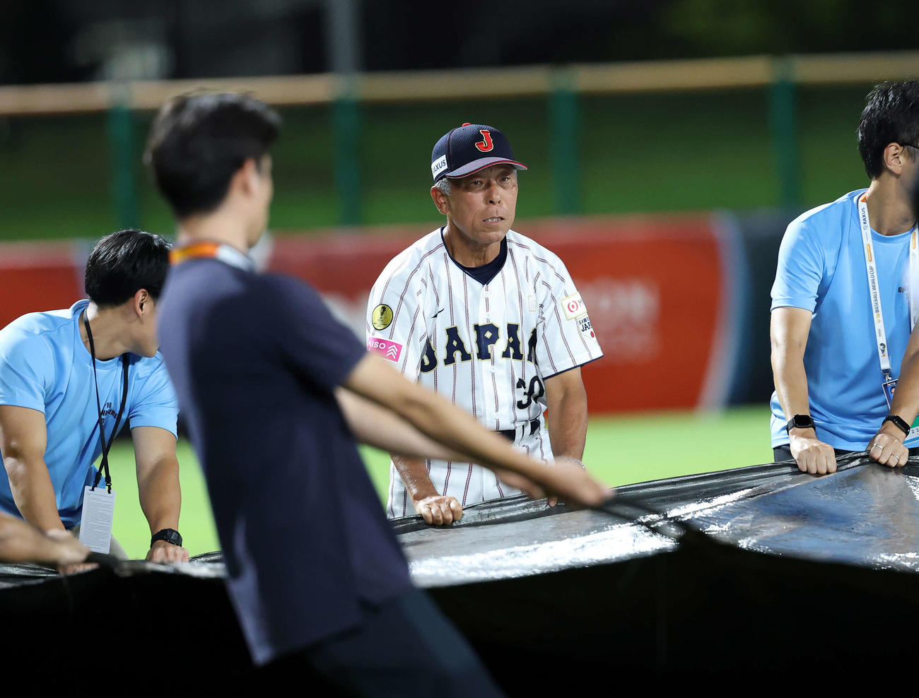 南アフリカ対日本　雨が上がりシートはがしを手伝う日本・小倉監督（撮影・鈴木正人）