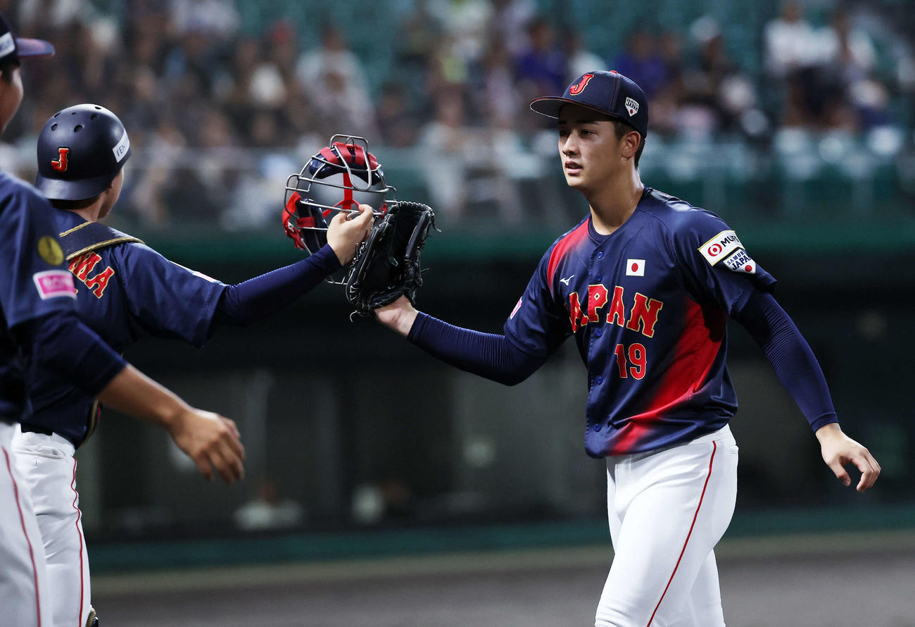 日本対プエルトリコ　1回裏、プエルトリコの攻撃を抑えタッチする日本・横山（左）と奥村頼（撮影・鈴木正人）